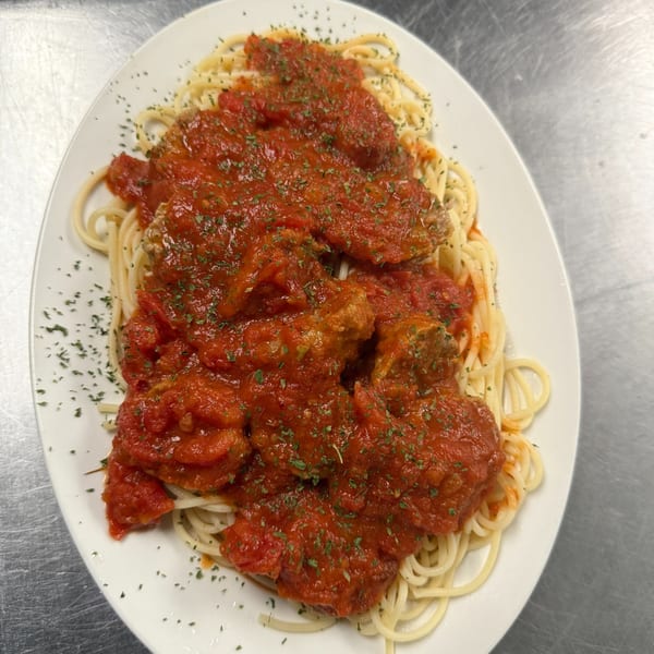 Spaghetti with meatballs and rich red tomato sauce, garnished with parsley on a white plate.